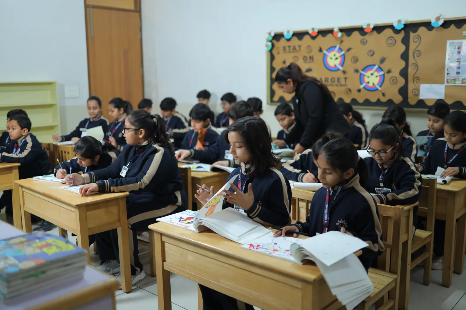 A classroom of learners working at wooden desks.