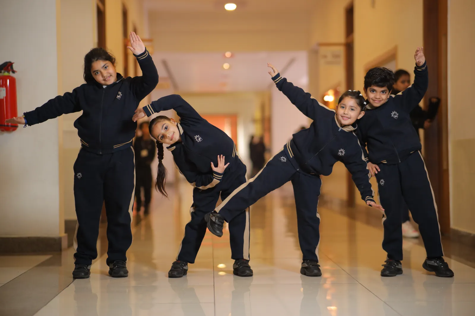 Four learners stretching together in a bright school corridor.