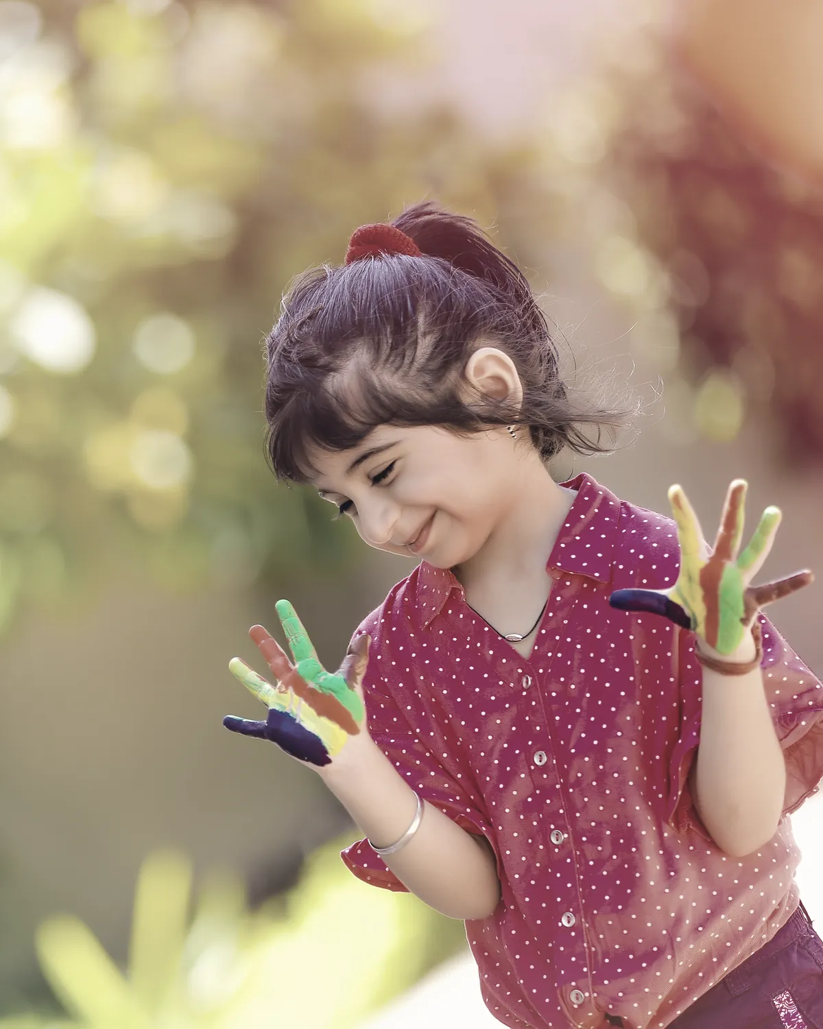 A learner looking at her own hands, painted in every colour.