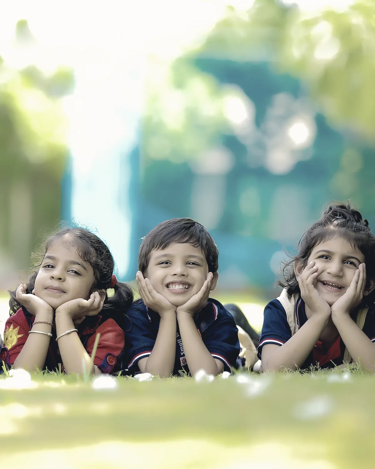 Five learners lying on the grass outdoors, chins on their hands.